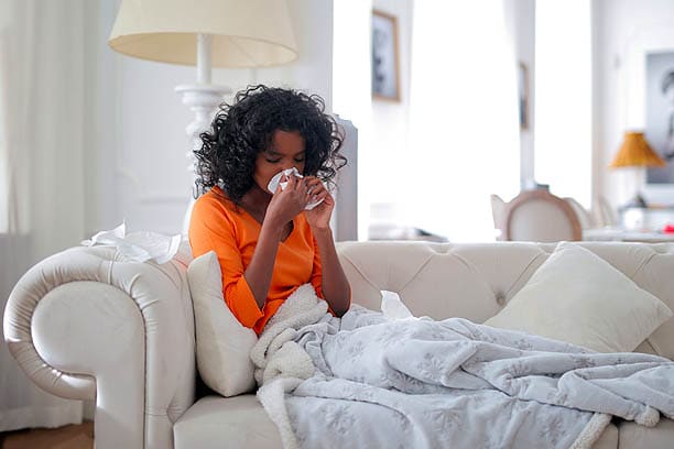 flu vaccine in 2022 woman on couch couging